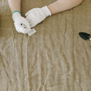 person in white gloves writing on plant tags